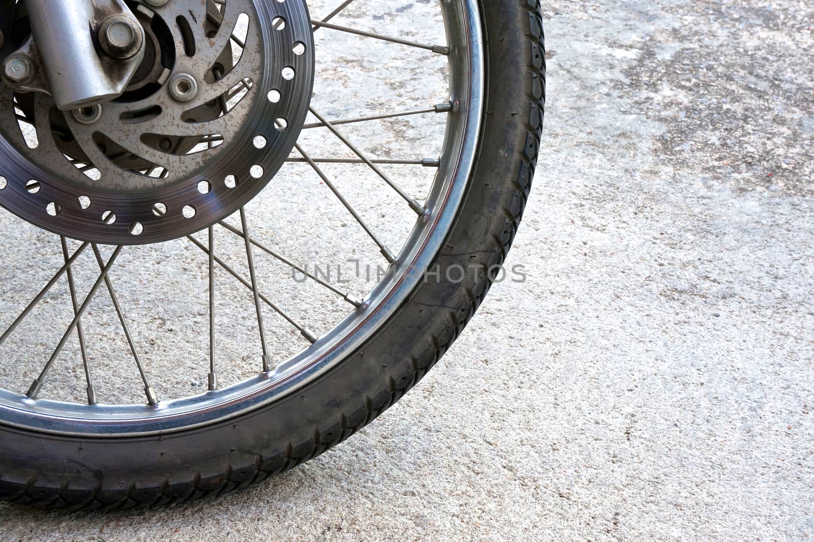 Old black wheel of motorcycle and disc brake on the left.