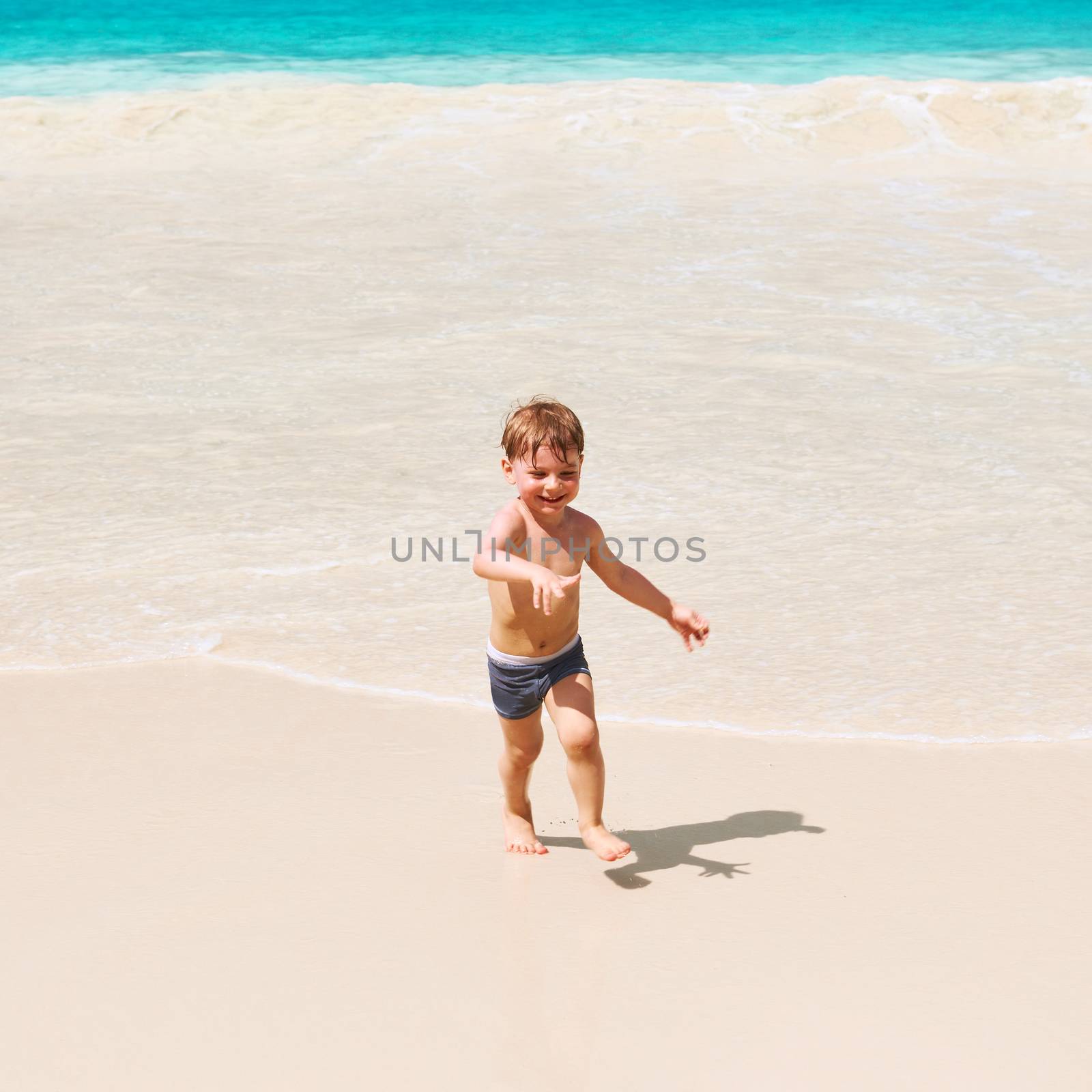 Two year old baby boy playing on beach at Seychelles