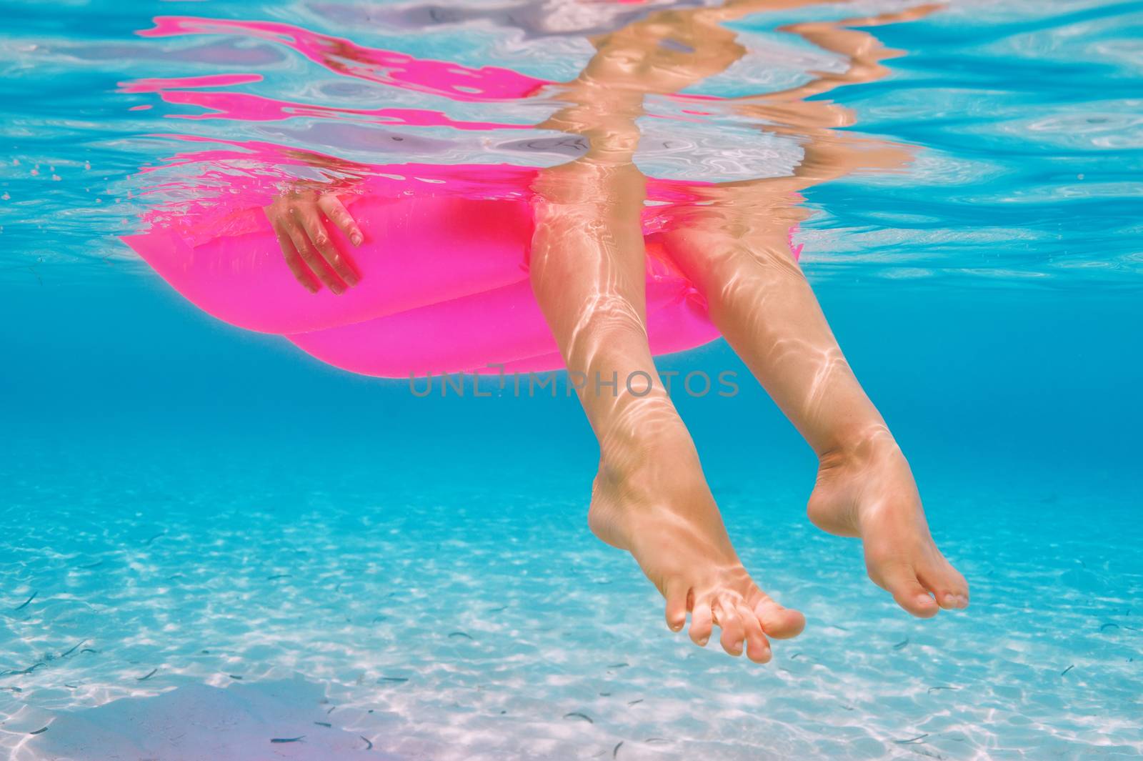 Woman relaxing on inflatable mattress at the beach, view from underwater