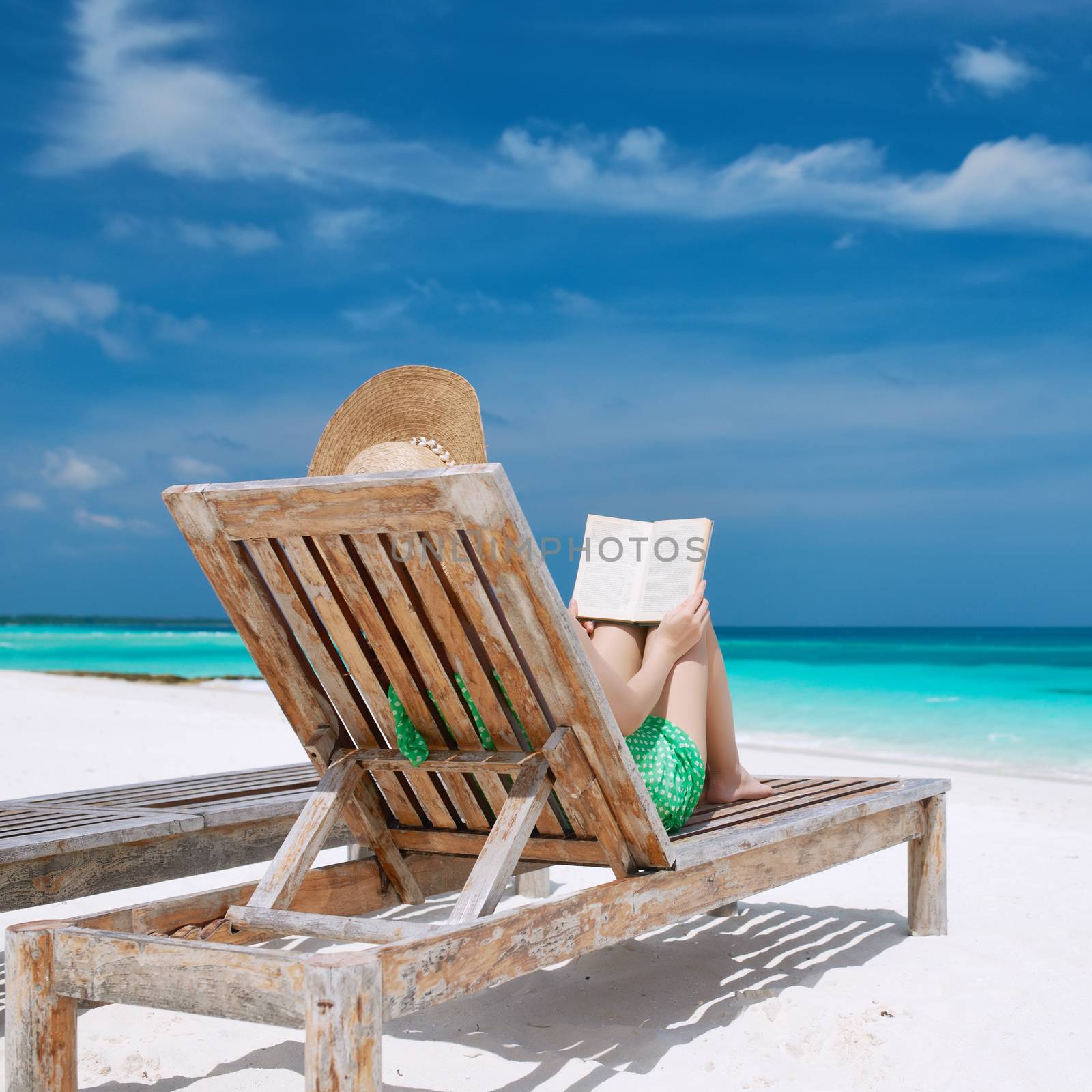 Young woman reading a book at beach by haveseen