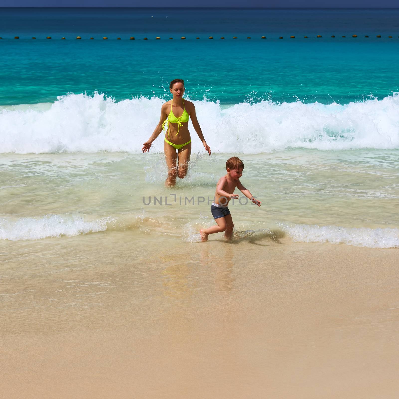 Mother and two year old boy playing on beach by haveseen