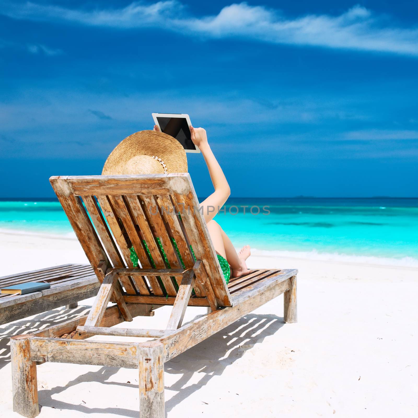 Young woman in hat with tablet pc at the beach