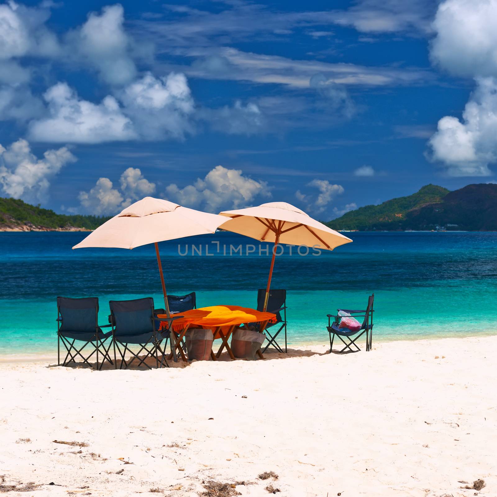 Tropical beach at Seychelles with picnic table and chairs by haveseen