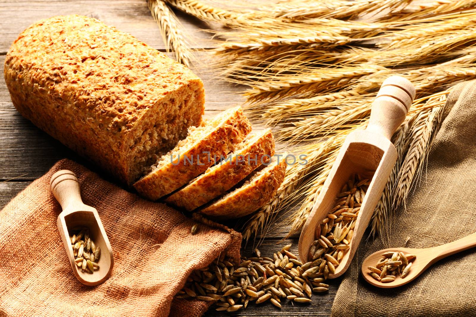 Rye spikelets and bread on wooden background