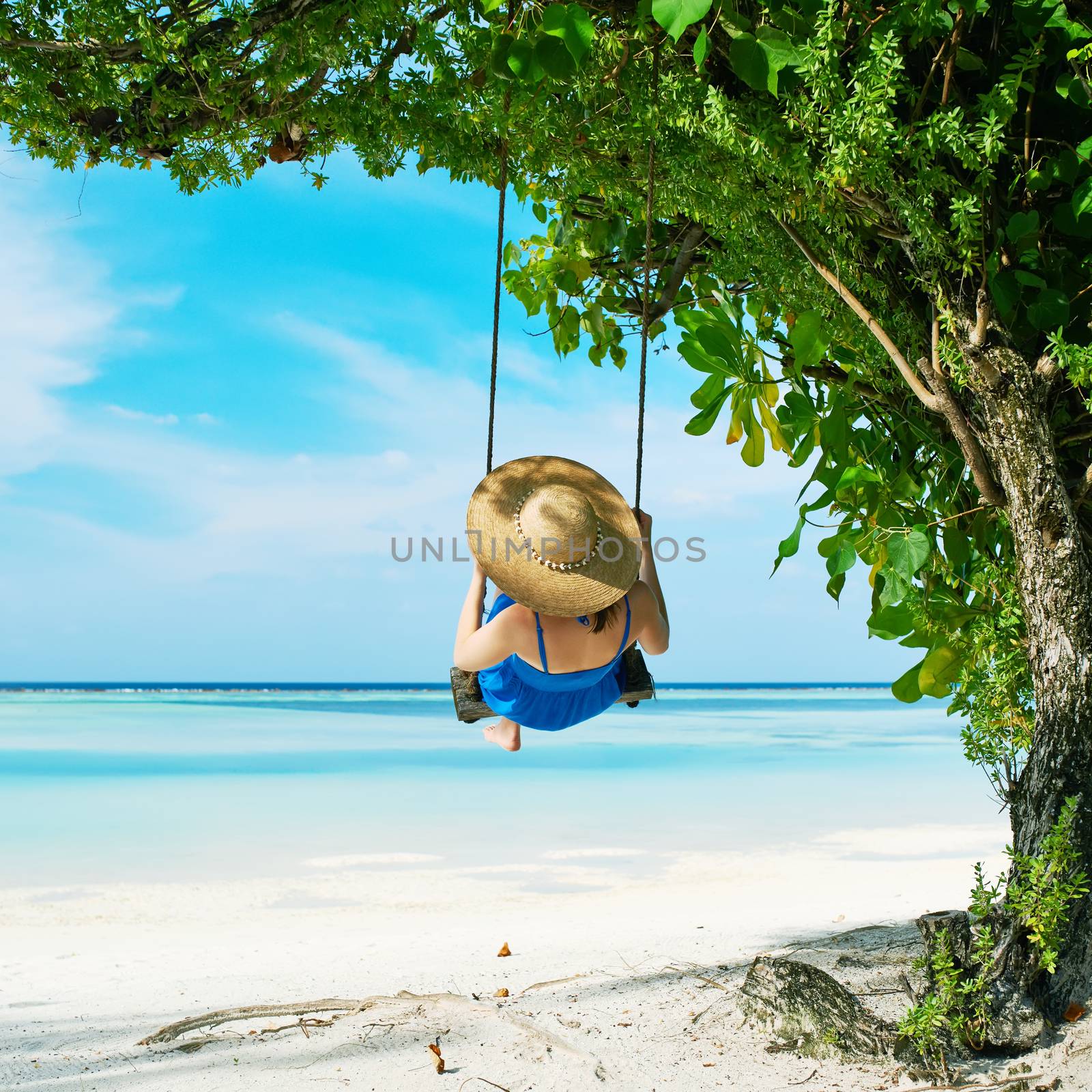 Woman in blue dress swinging at beach by haveseen