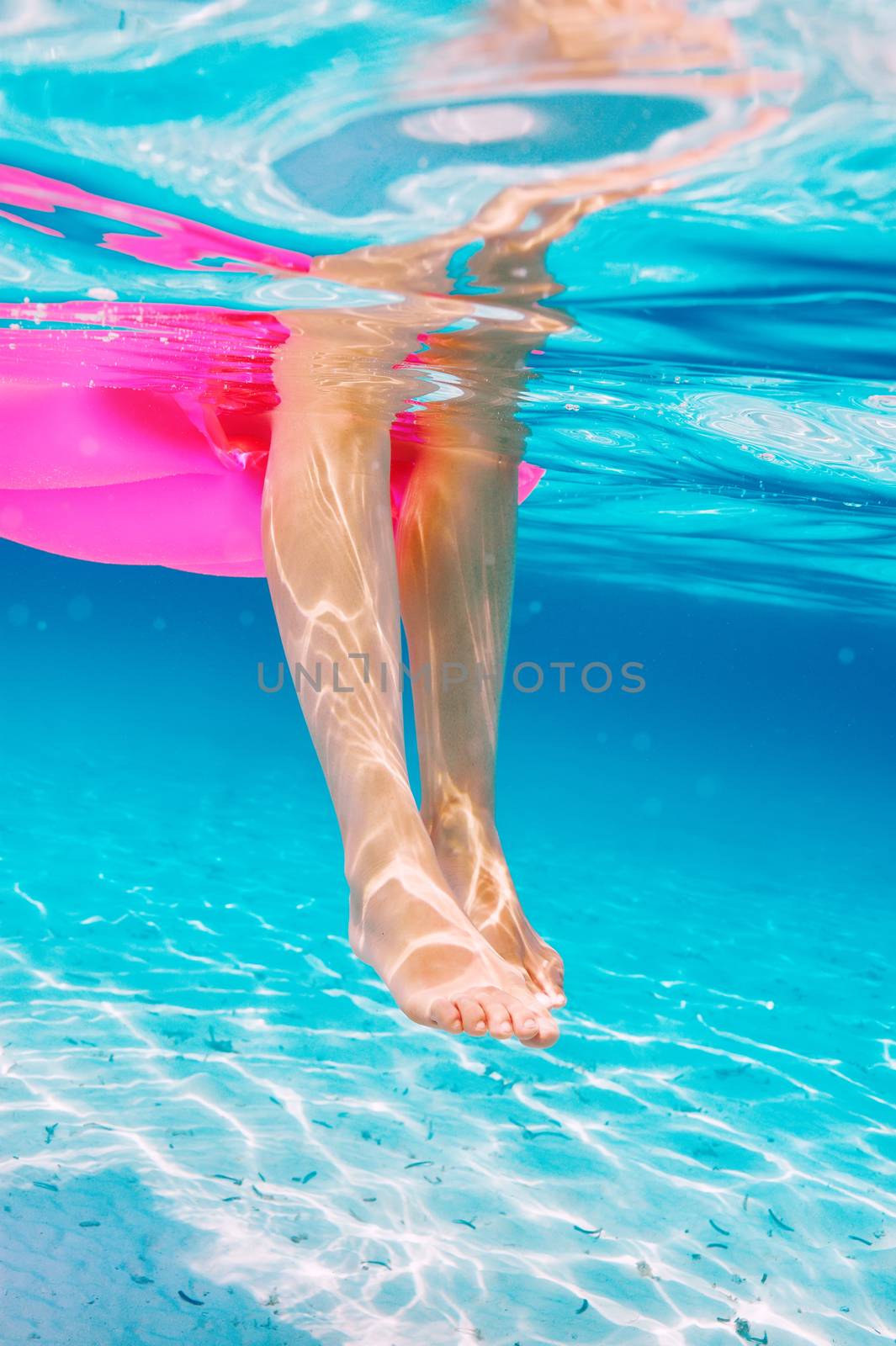 Woman relaxing on inflatable mattress at the beach, view from underwater