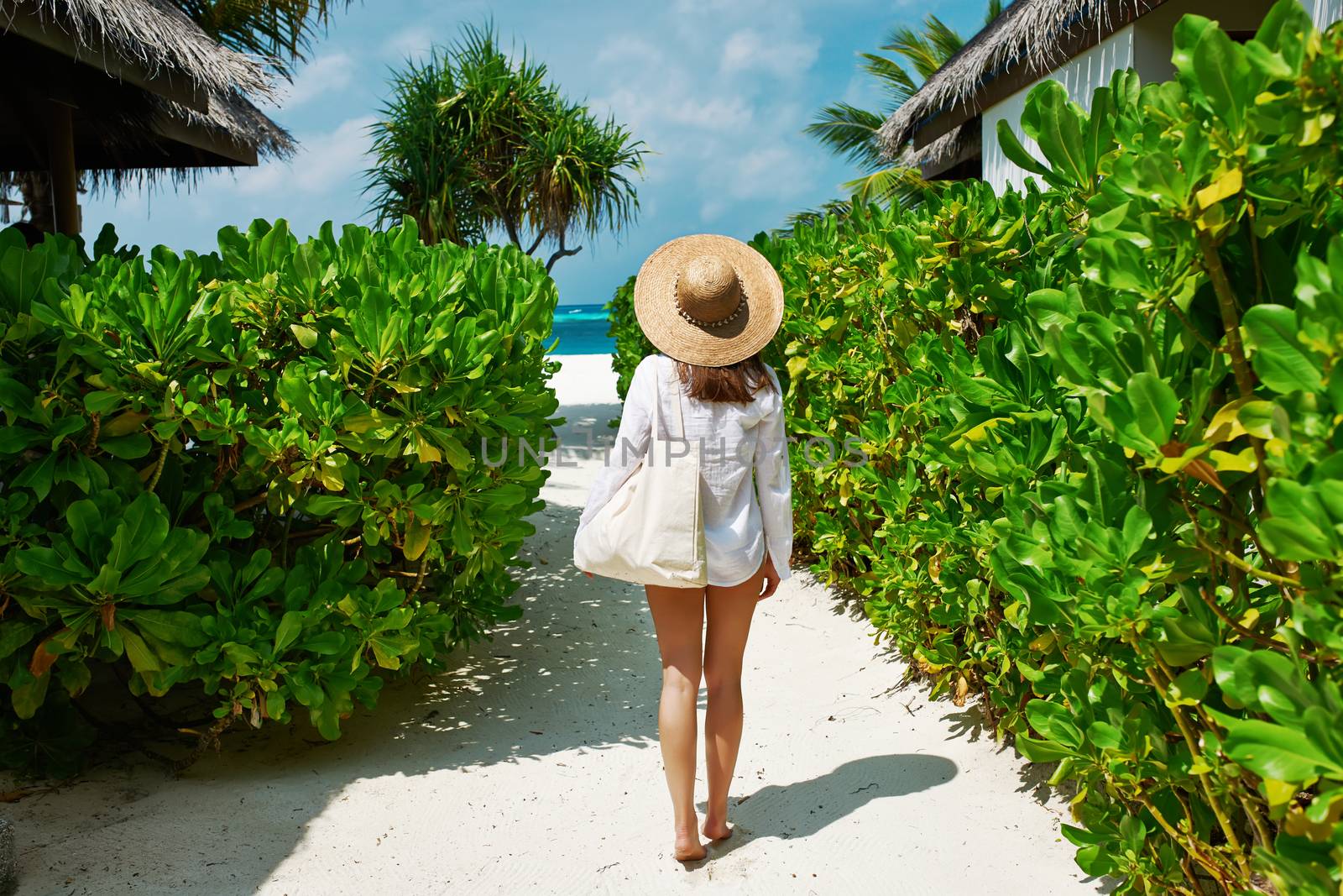 Woman with bag and sun hat going to the beach