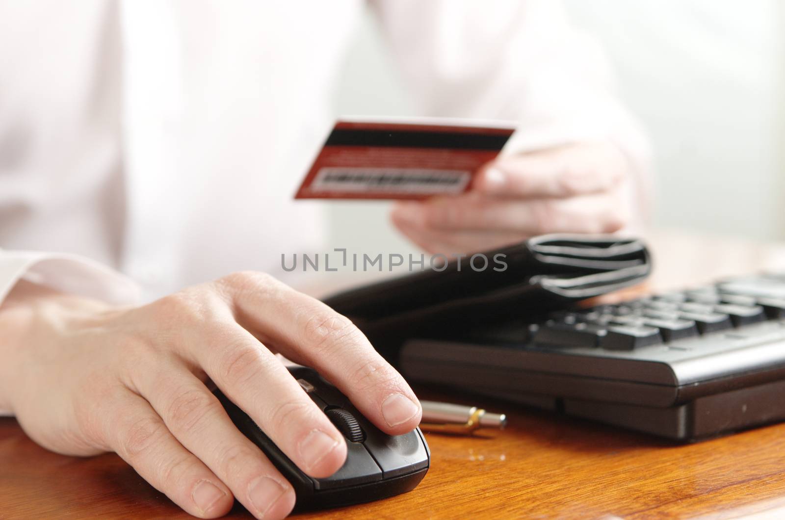 Hands of businessman with purse and bank card on the computer keyboard by Ravenestling