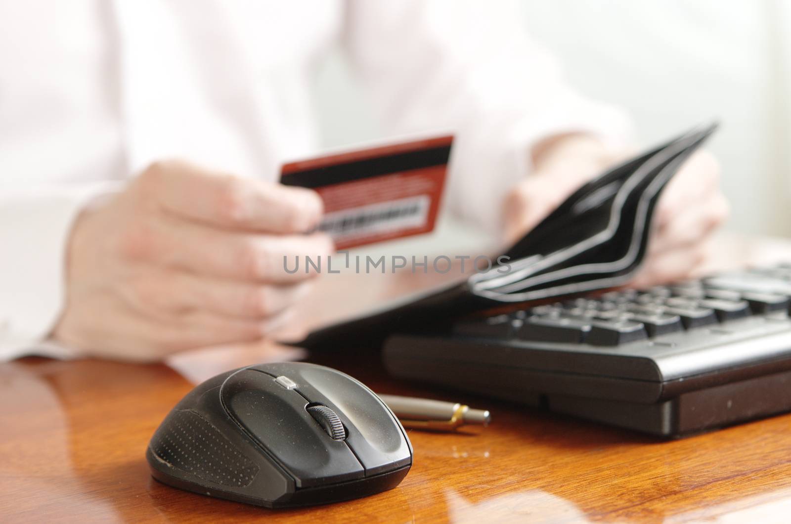 Hands of businessman with a purse and a bank card on the computer keyboard