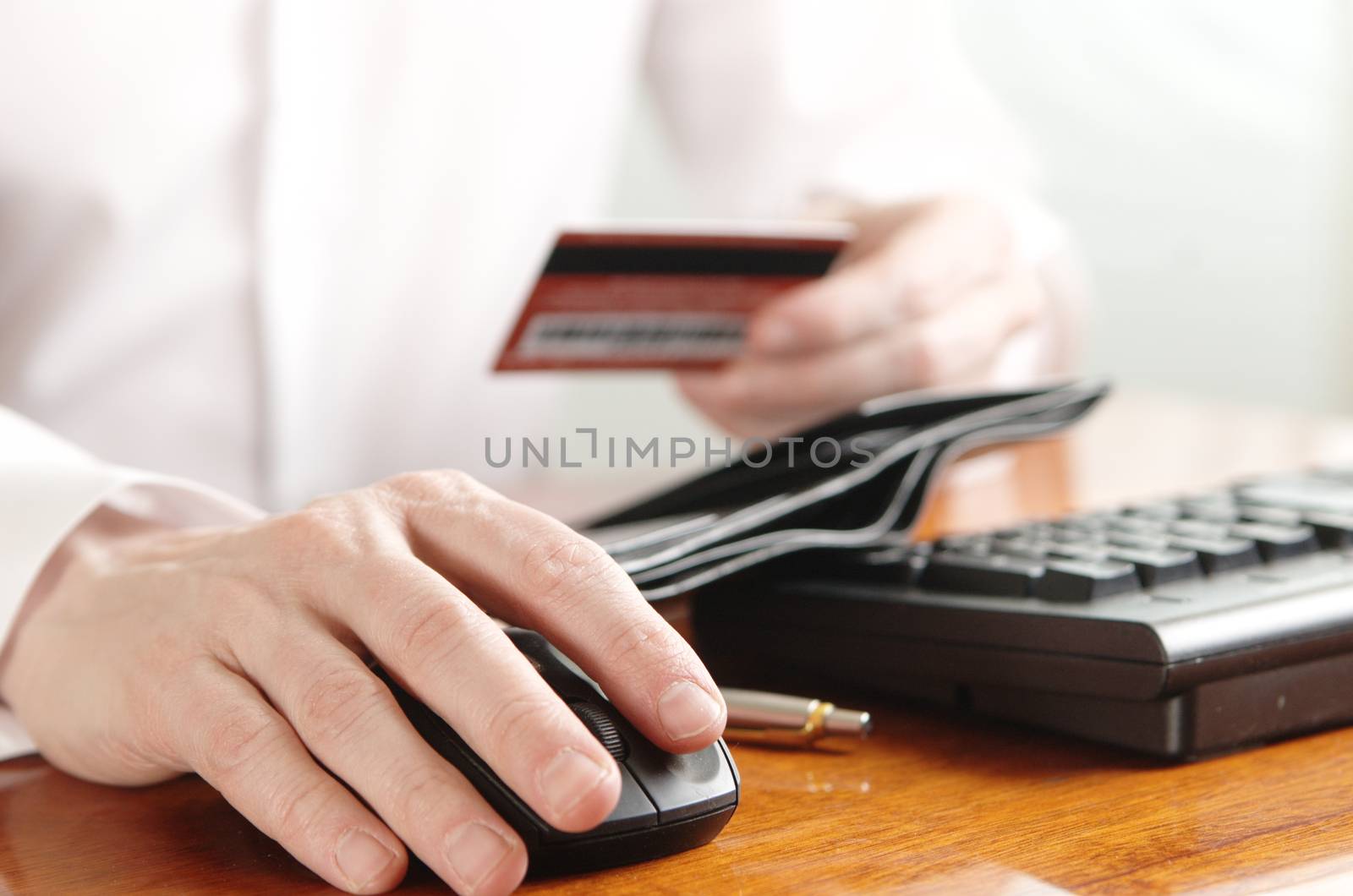 Hands of businessman with a purse and a bank card on the computer keyboard