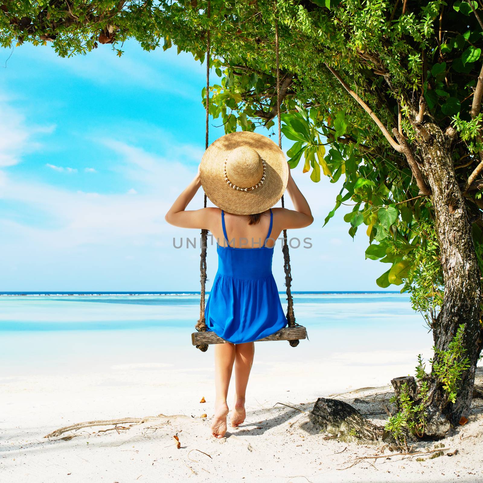 Woman in blue dress swinging at beach by haveseen