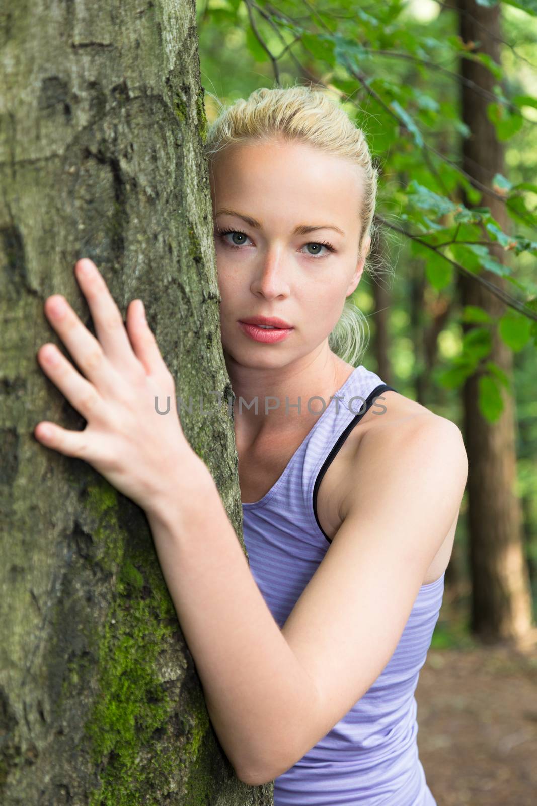 Relaxed young lady embracing a tree receiving life energy from the nature.