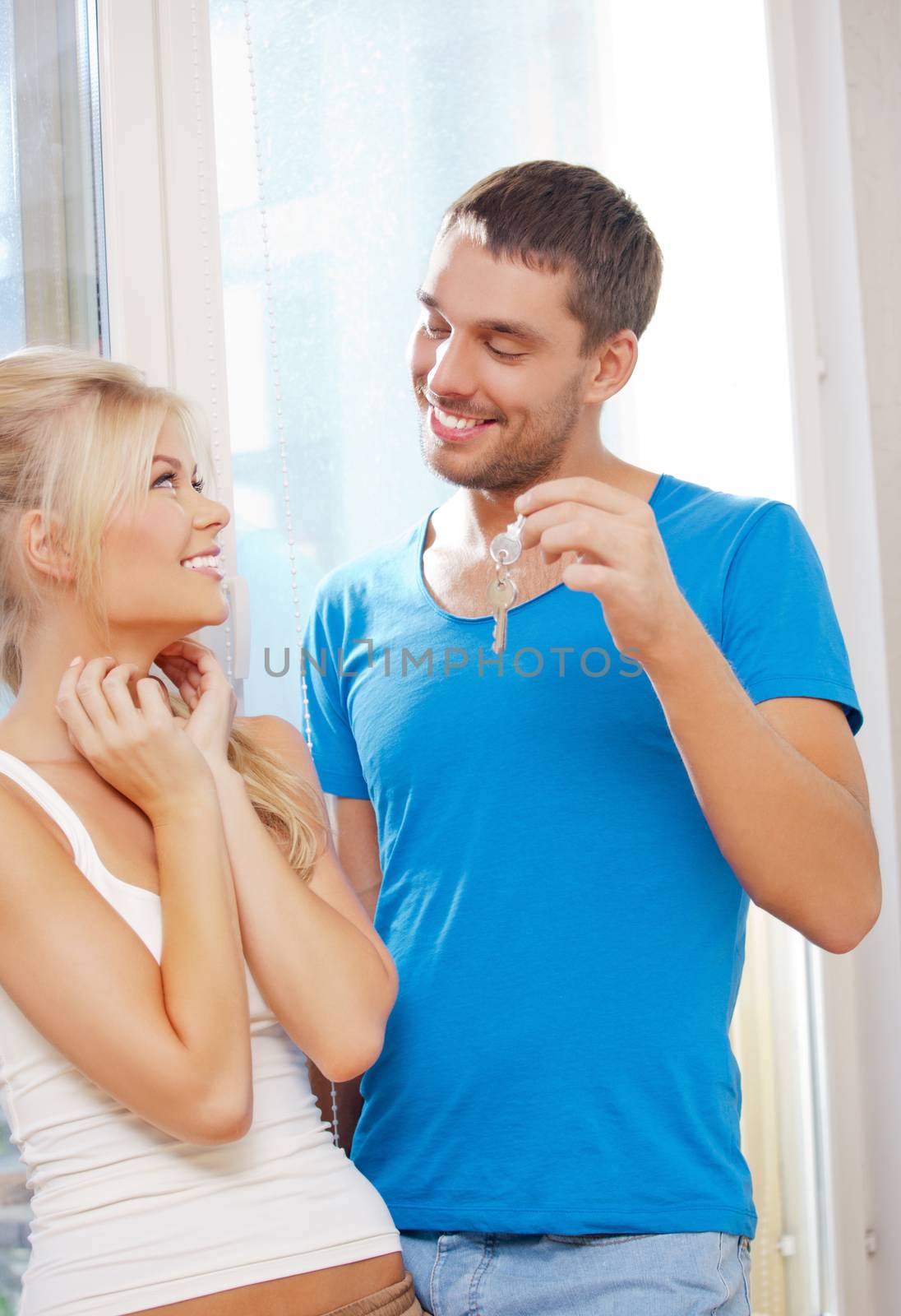 bright picture of happy couple with keys (focus on man)