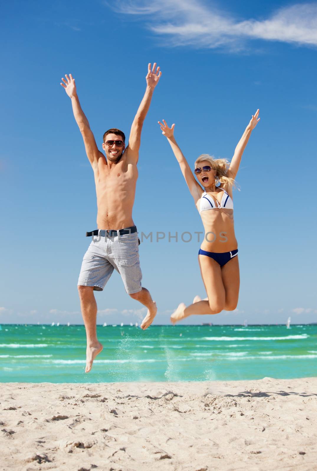 happy couple jumping on the beach by dolgachov