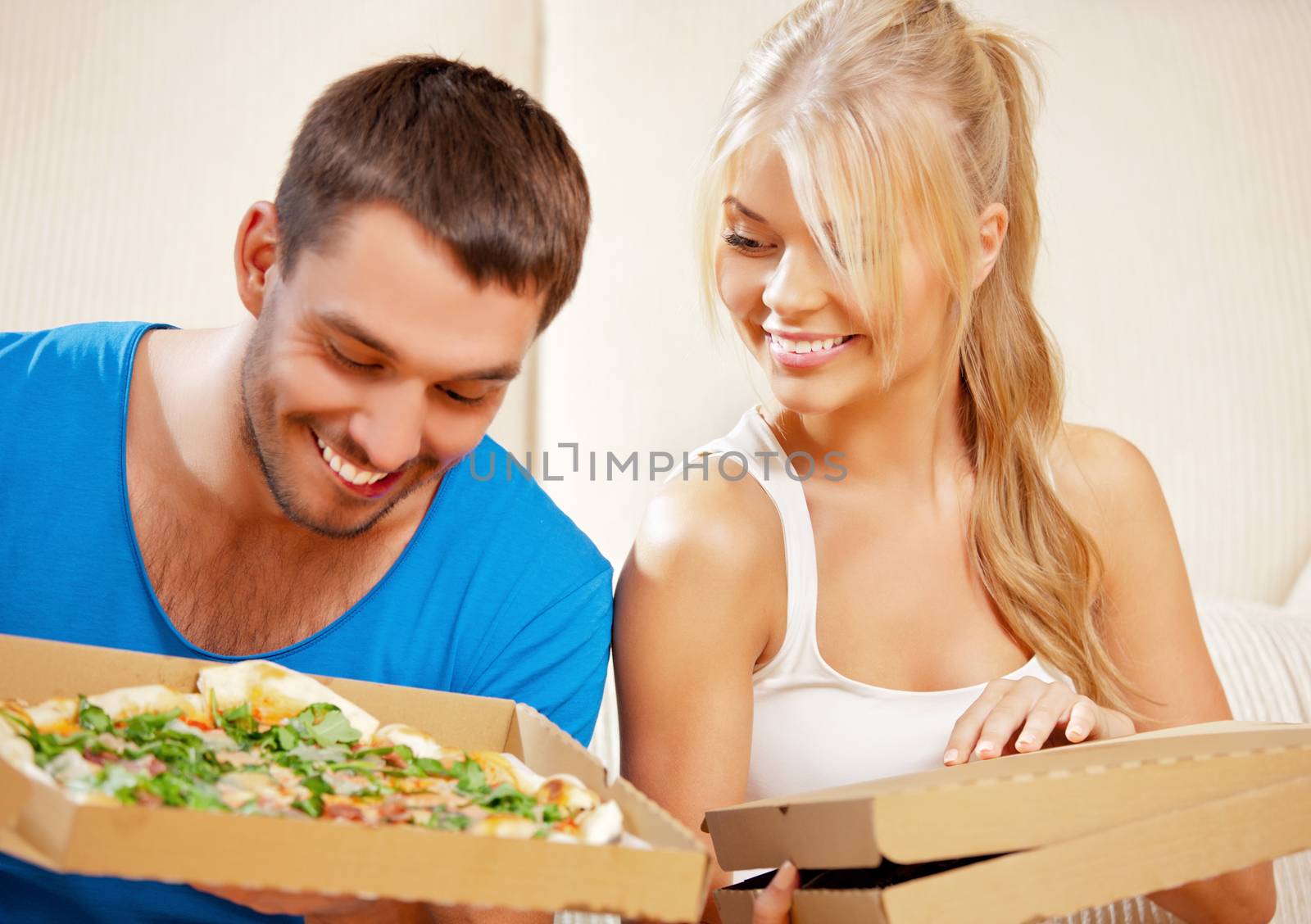 picture of happy romantic couple eating pizza at home (focus on woman)