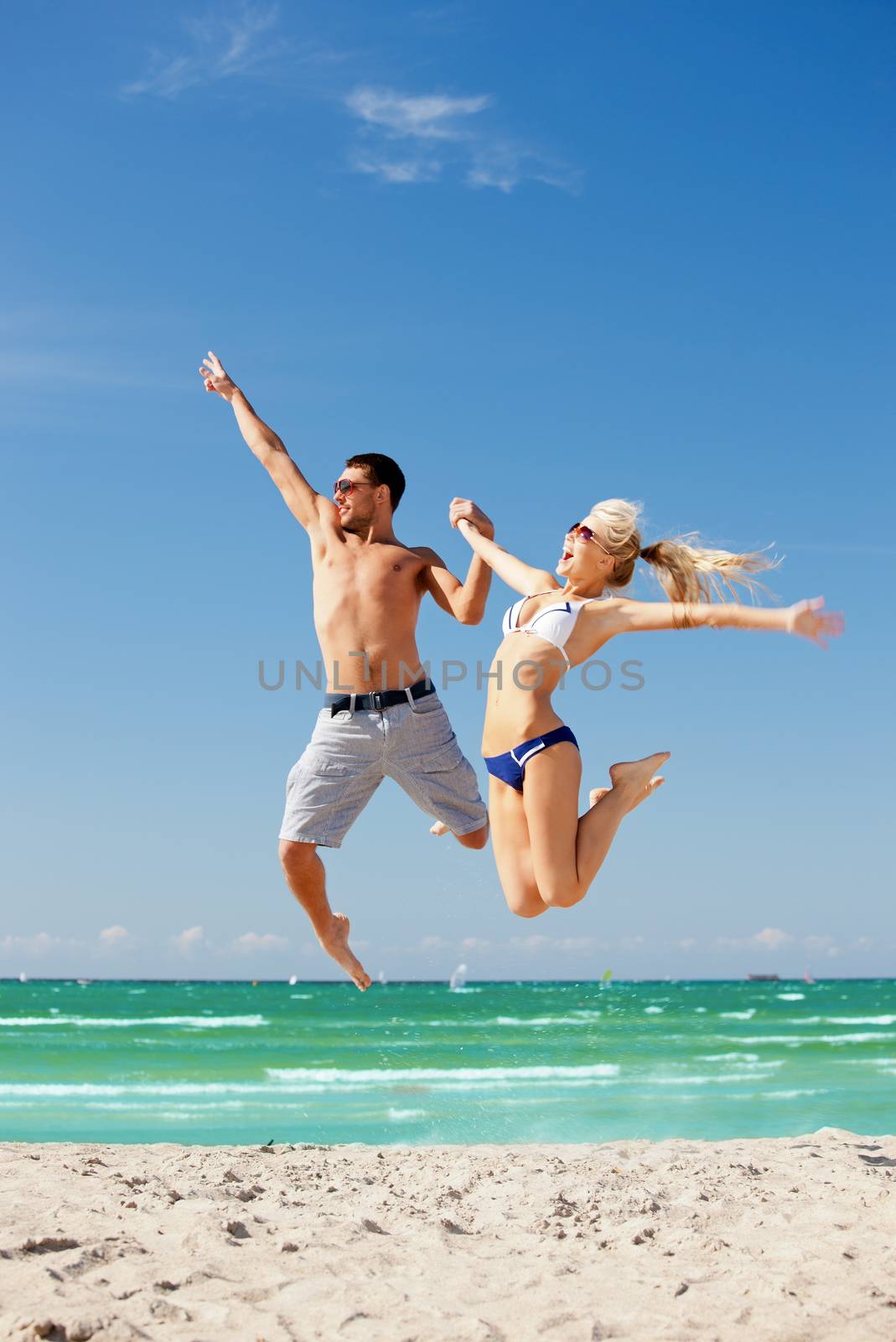 picture of happy couple jumping on the beach (focus on man).