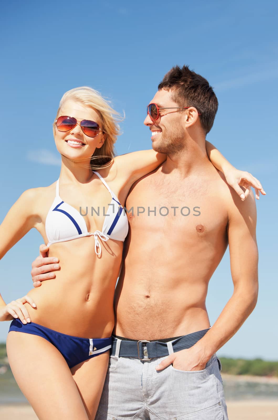 happy couple in sunglasses on the beach by dolgachov