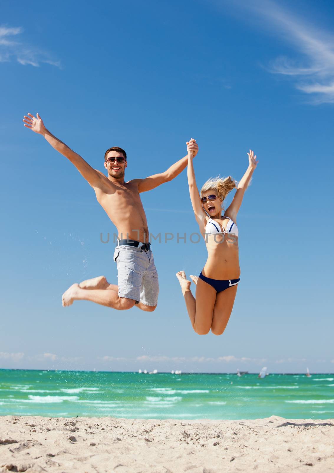 picture of happy couple jumping on the beach.