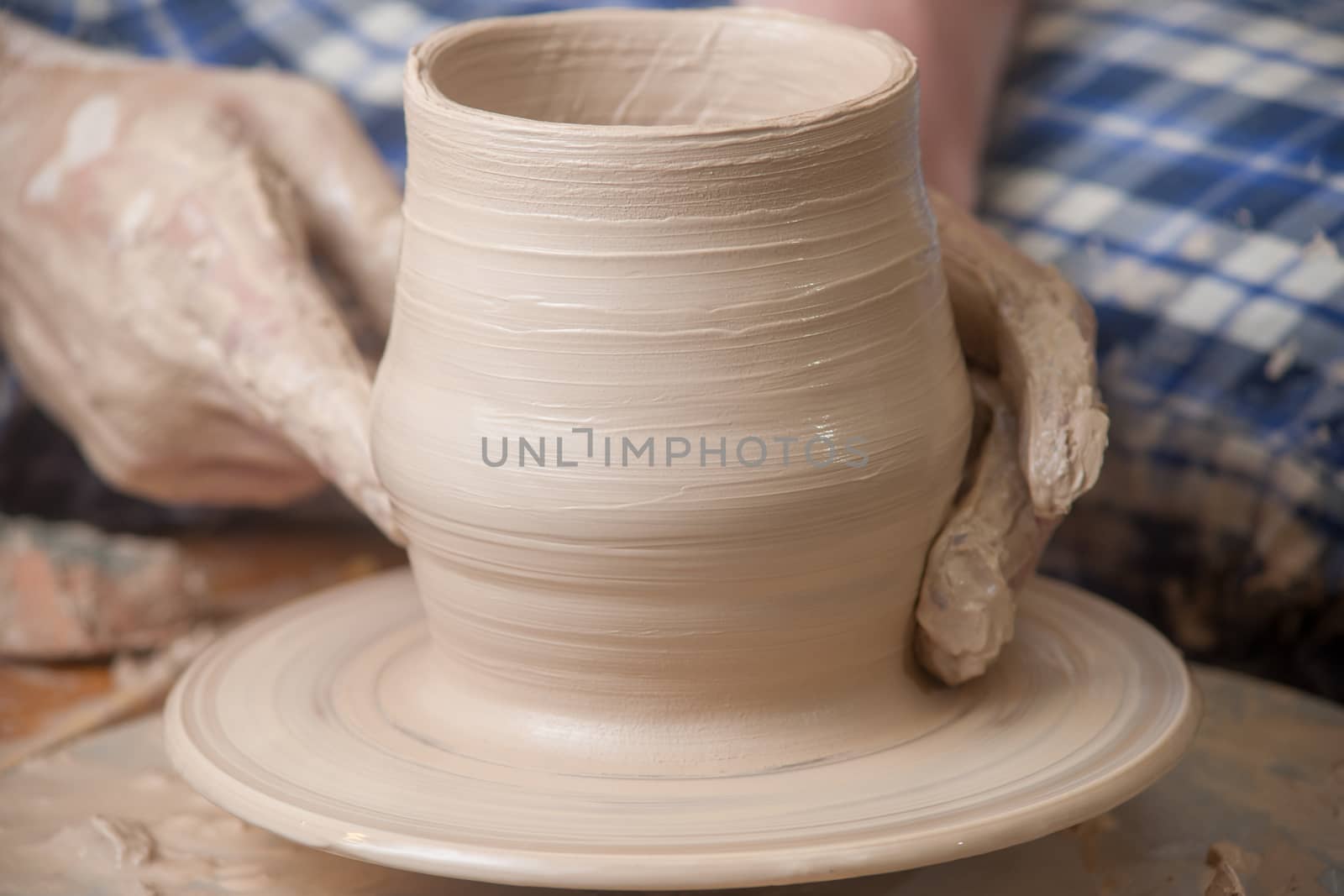 Hands of a potter, creating an earthen jar on the circle