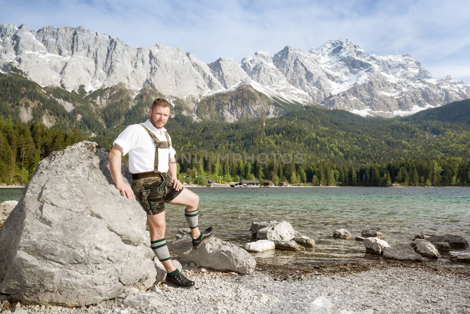 A traditional bavarian man at lake Eibsee with the Zugspitze mountain in the background