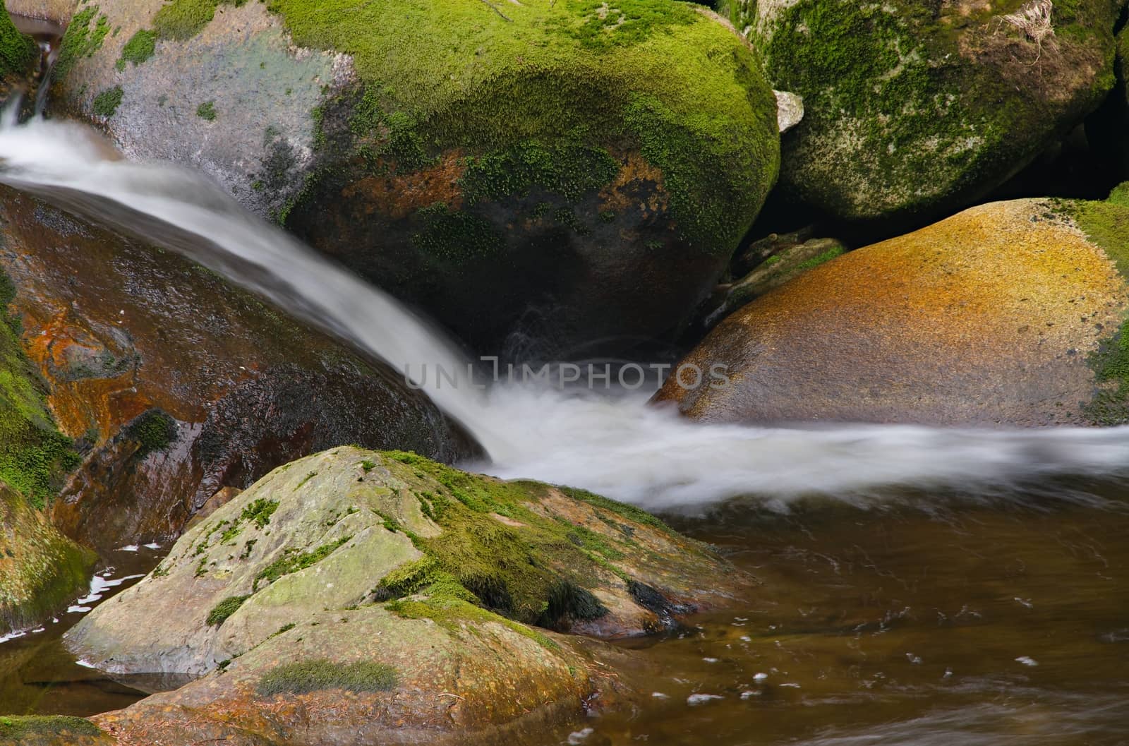 Detail of small beautiful cascade between mossy stones. 