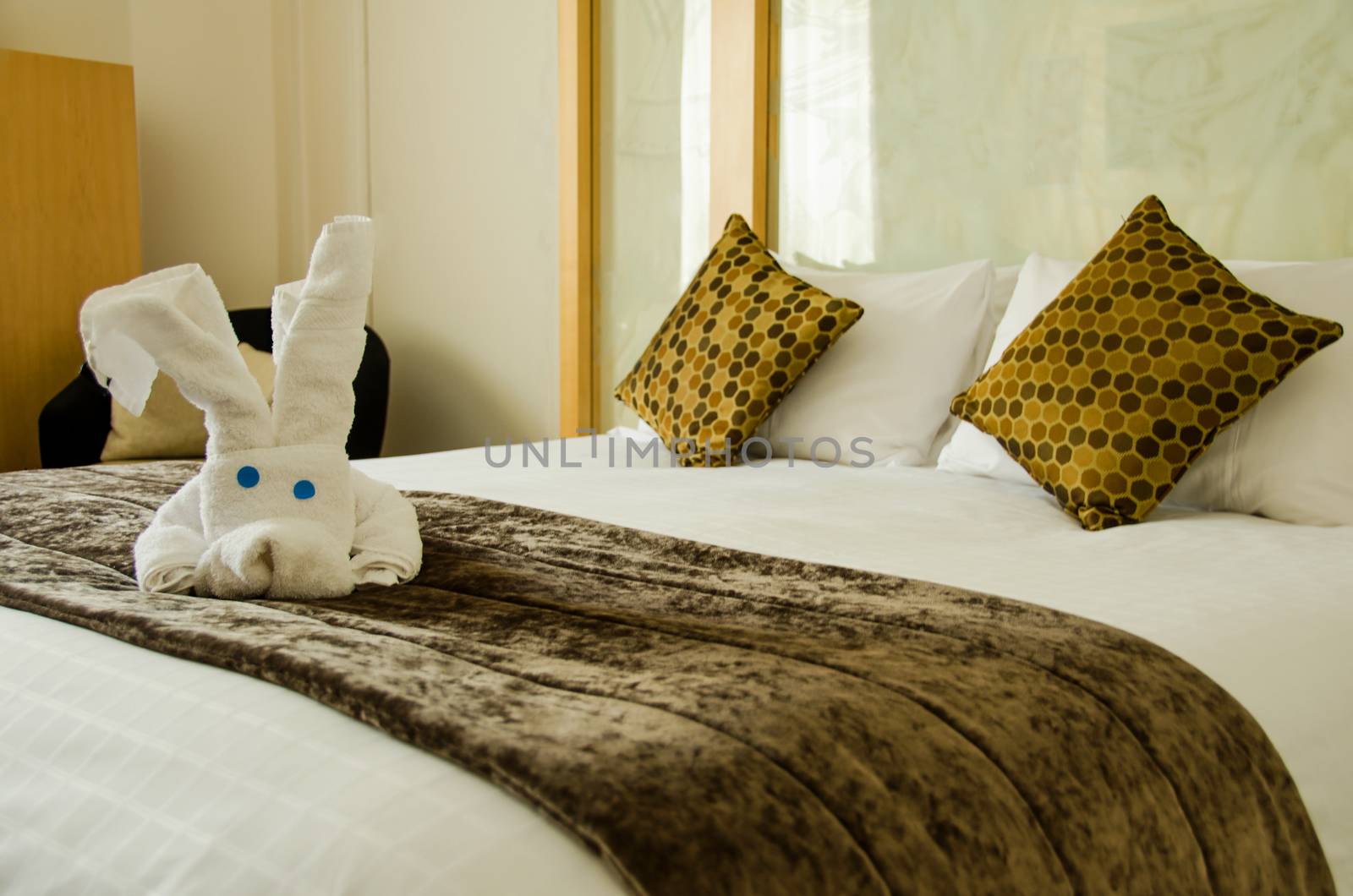 White brown bedroom with white plush toy on the brown bed cover.