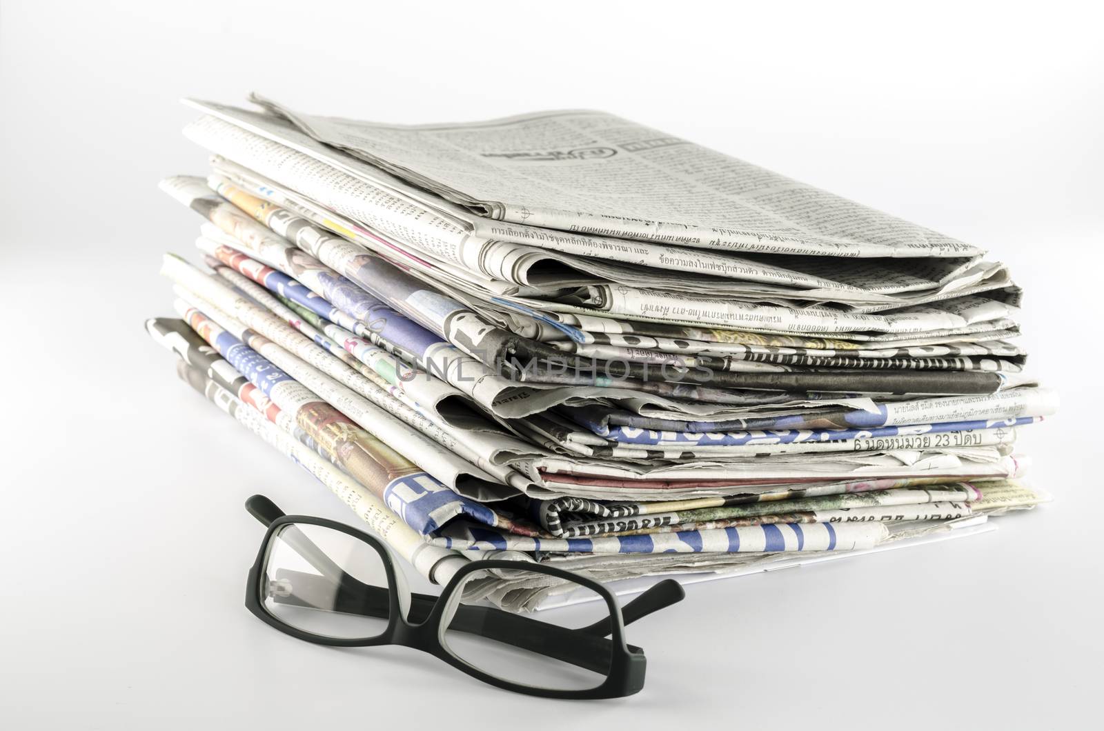 stack of newspaper with glasses on a white background