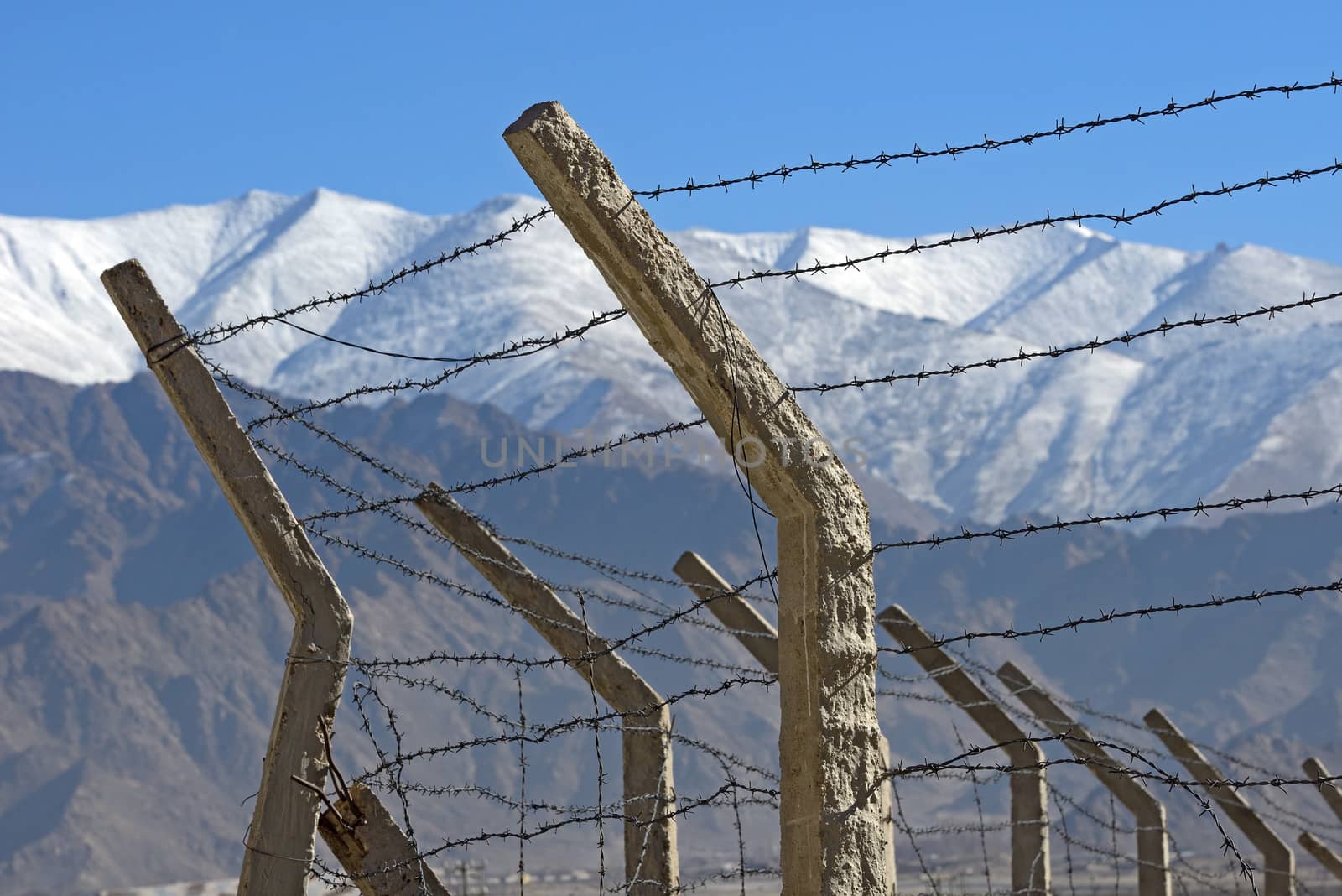 Barbed wire fence in winter with snow mountain background by think4photop