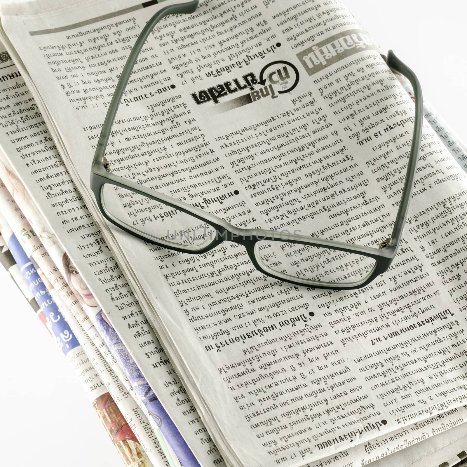 stack of newspaper with glasses on a white background