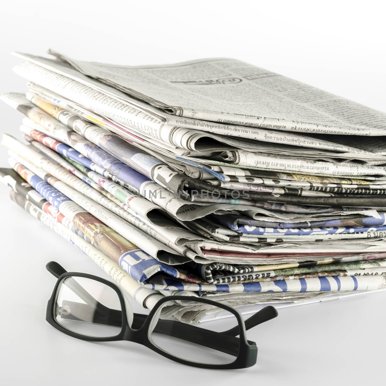 stack of newspaper with glasses on a white background