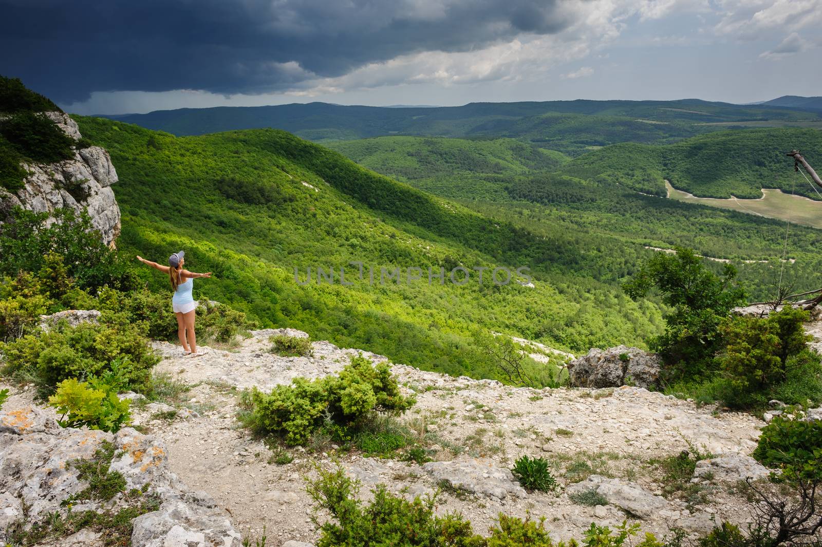 Young woman enjoying the storm at the edge of the cliff, Crimea, Ukraine