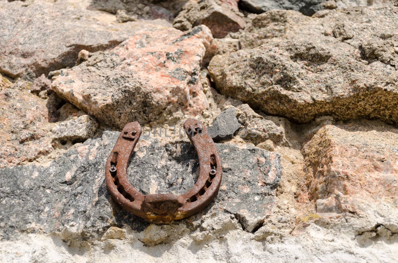 old iron fortune symbol horseshoe on stone wall by sauletas