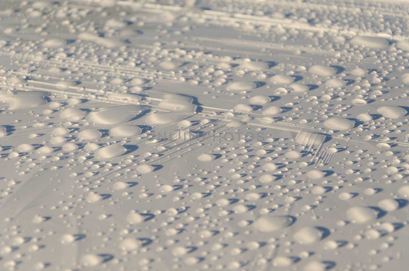 rain water drops glisten on white material surface background.