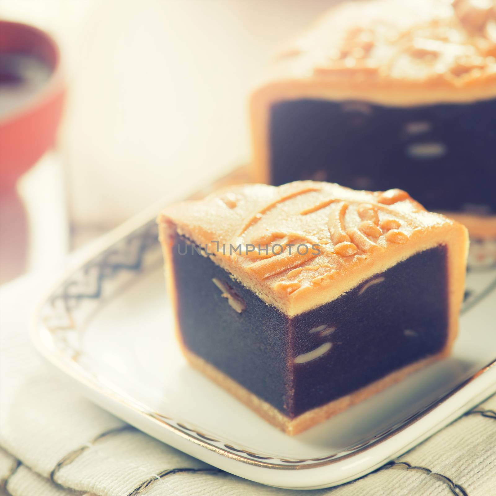 Traditional red beans paste mooncakes on white plate with teacup. Chinese mid autumn festival foods. 