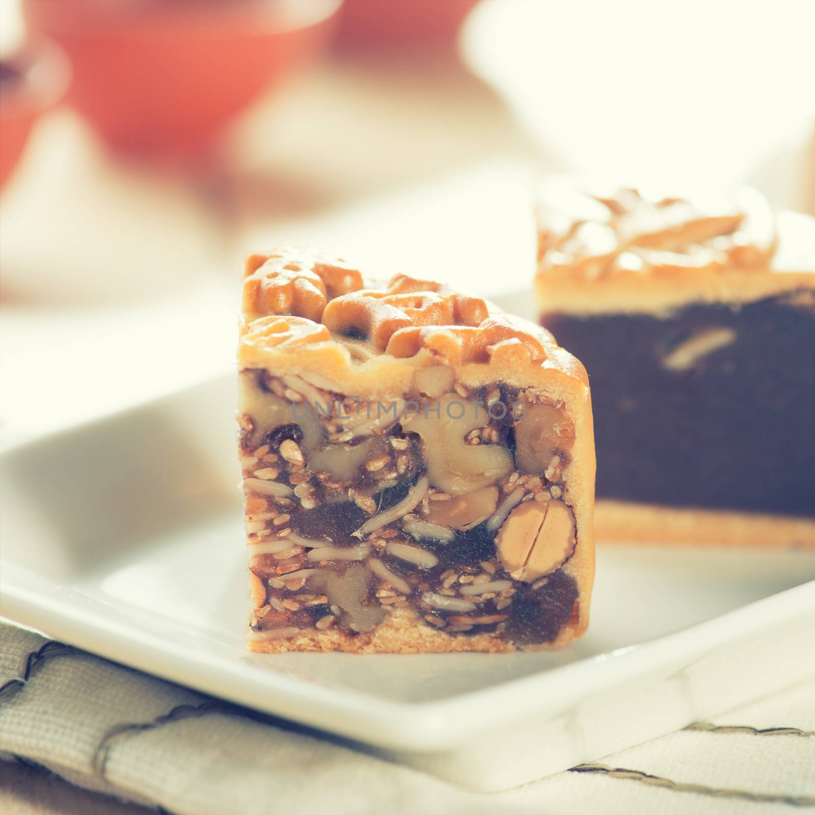 Traditional mooncakes on white plate with teacup. The Chinese words on the mooncakes means assorted fruits nuts, not a logo or trademark. Chinese mid autumn festival foods. 