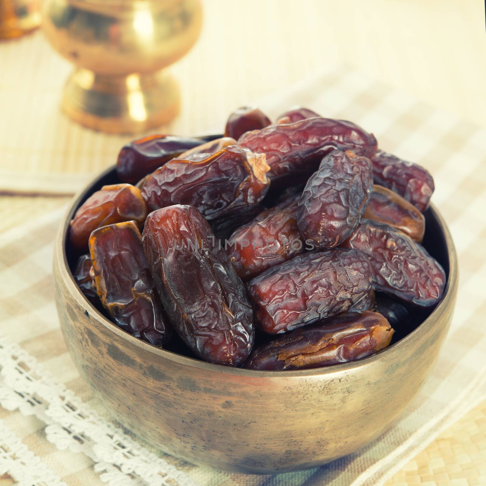 Dried date palm fruits or kurma, ramadan food which eaten in fasting month. Pile of fresh dried date fruits ready to eat in metal bowl.