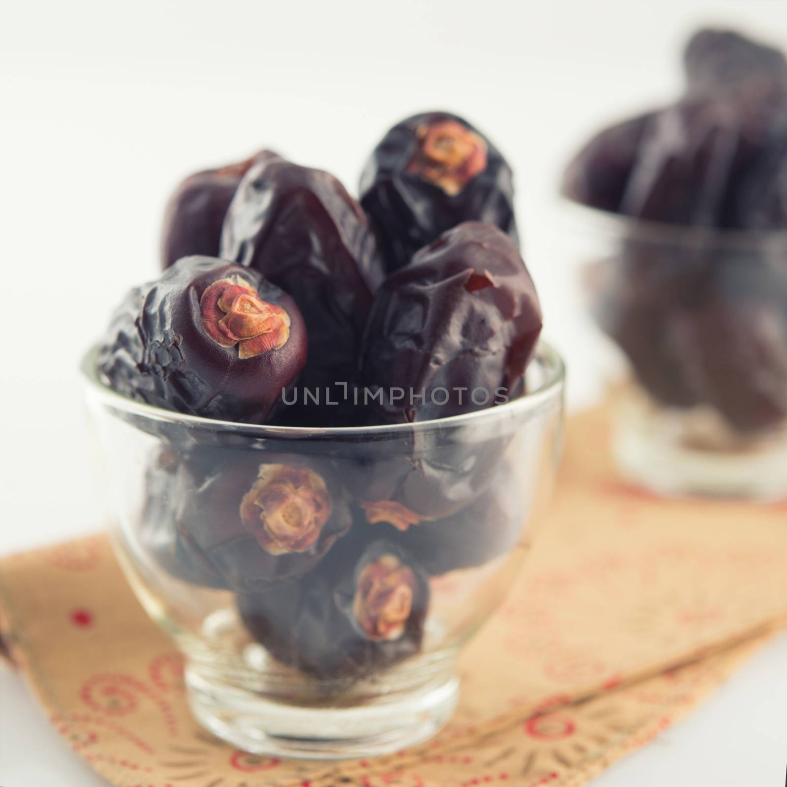 Dates fruit. Pile of dried date fruits in glass on plain background.