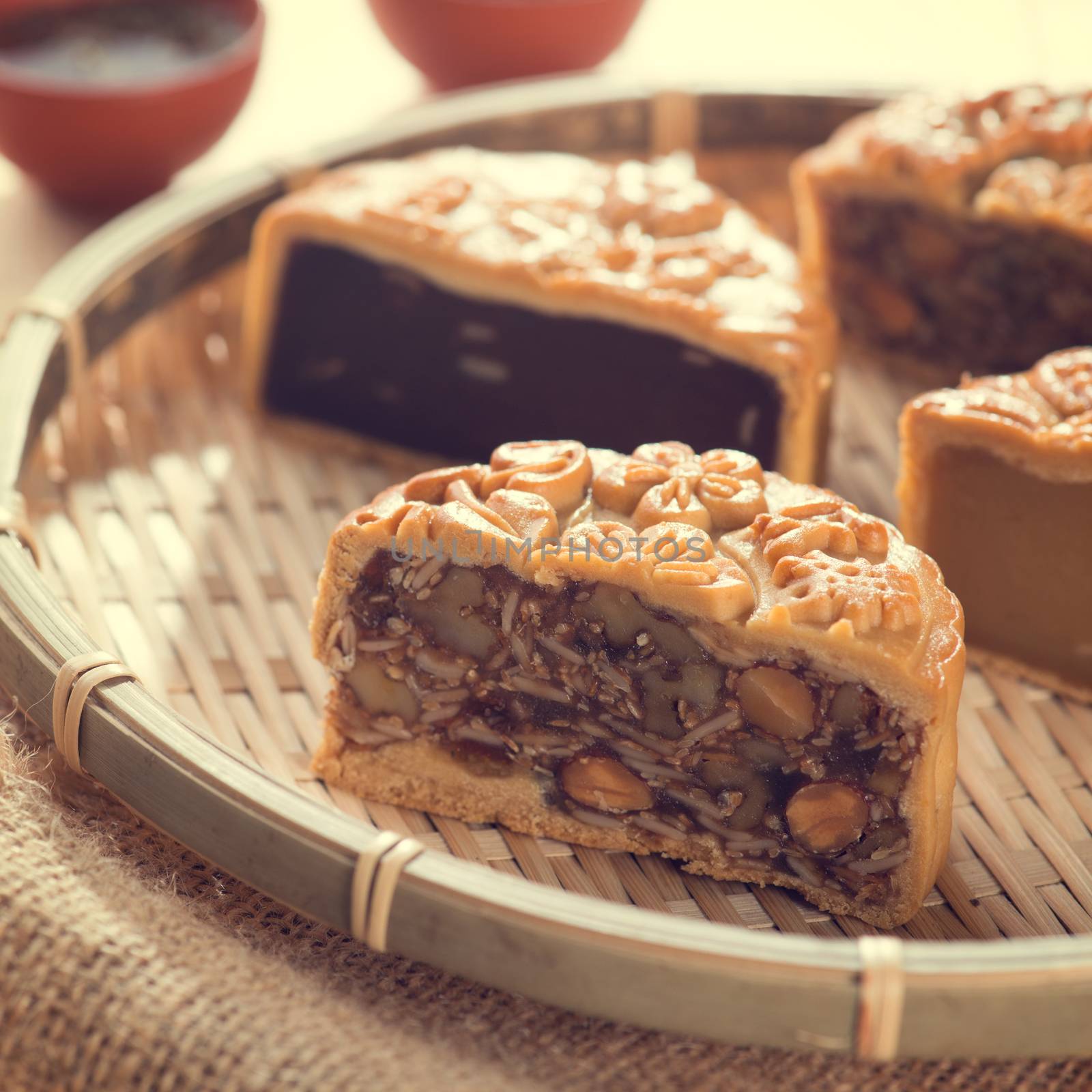 Chinese mid autumn festival foods. Traditional mooncakes on bamboo tray with teacup. The Chinese words on the mooncakes means assorted fruits nuts, not a logo or trademark.