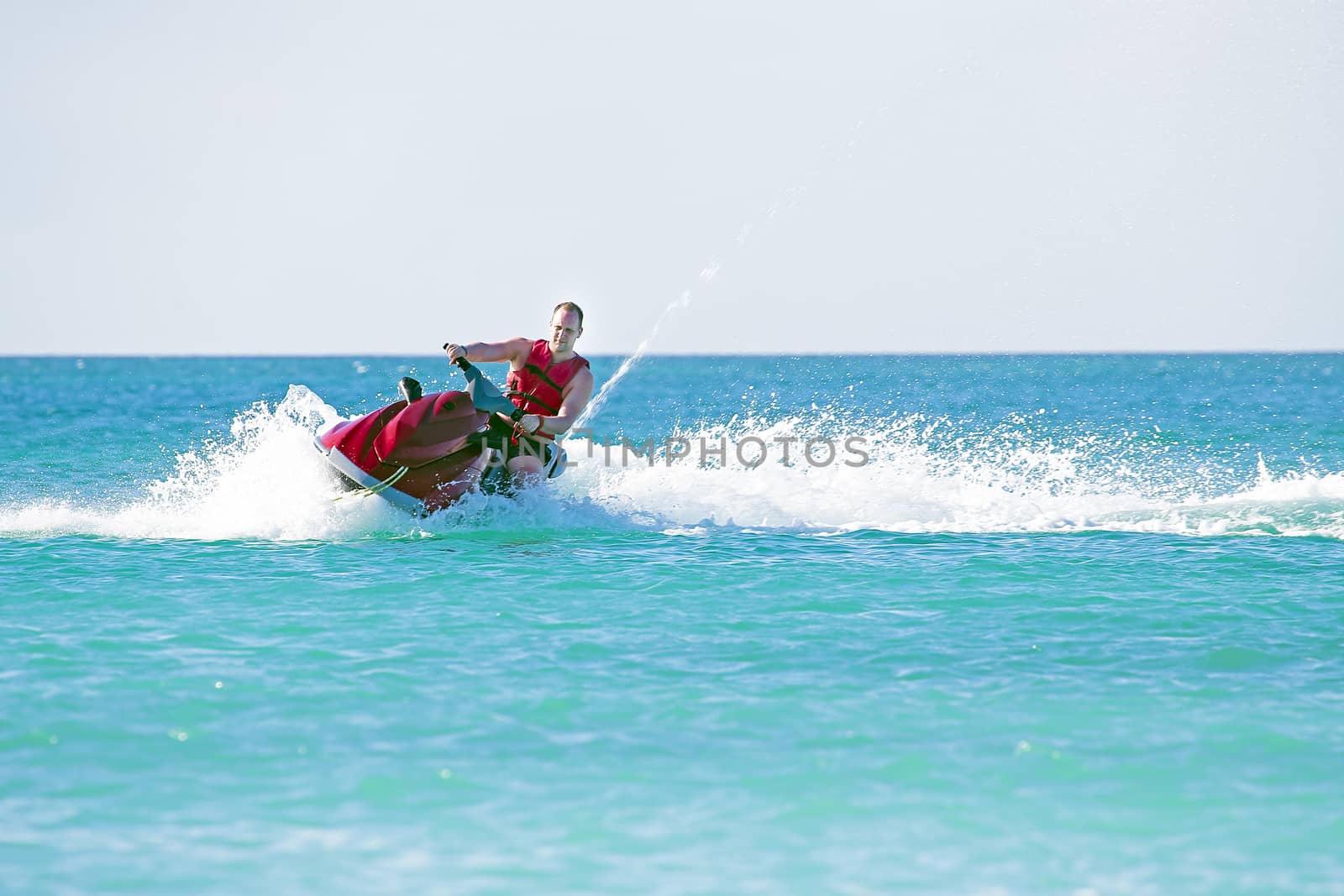 Young guy cruising on a jetski on the caribbean sea