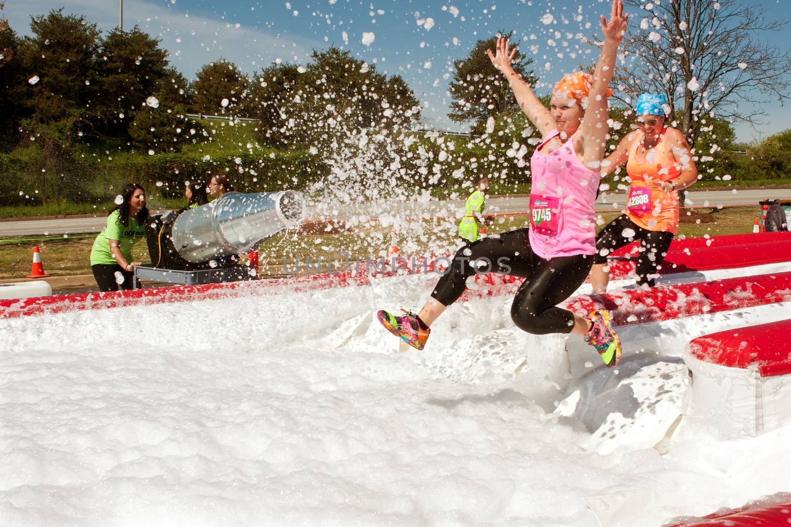 Atlanta, GA USA - April 5, 2014:  Young women get sprayed with bubbles jumping into a huge foam pit, as they take part in the Ridiculous Obstacle Challenge 5k race.