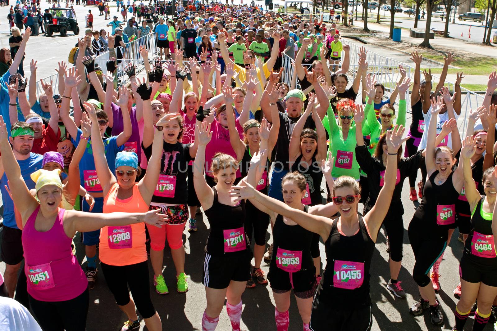 Atlanta, GA, USA - April 5, 2014:  A throng of excited runners gathered at start line, jubilantly waves to camera at the Ridiculous Obstacle Challenge (ROC) 5k race.