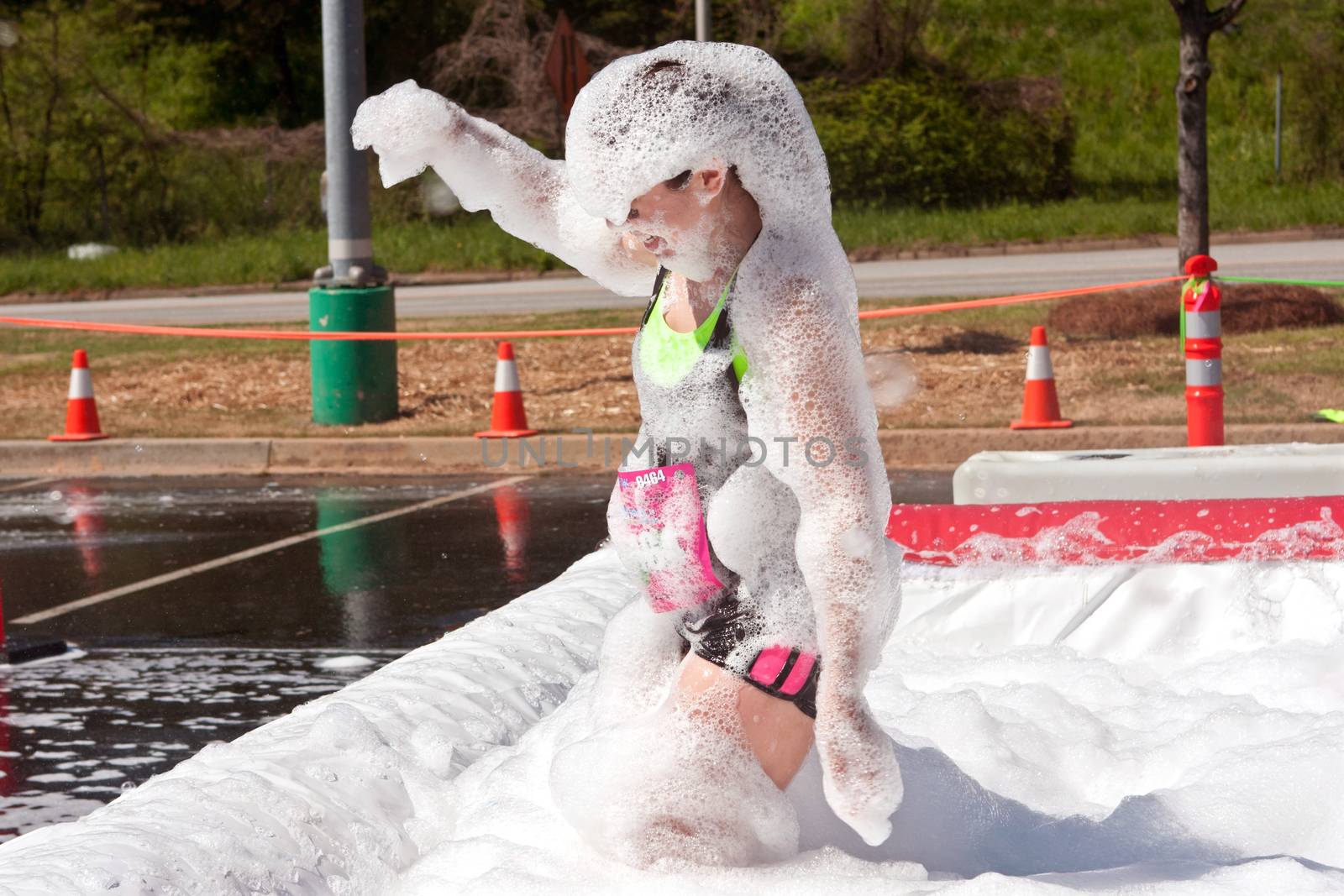 Atlanta, GA USA - April 5, 2014:  A young woman emerges from the foam pit covered head to toe in bubbles, at   the Ridiculous Obstacle Challenge (ROC) 5k race.