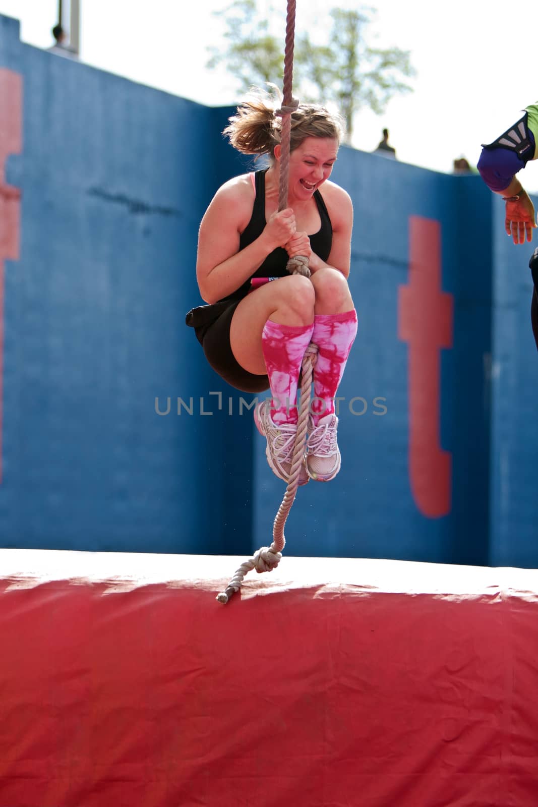 Atlanta, GA USA - April 5, 2014:  A young woman swings a rope across an obstacle in one of the events at the Ridiculous Obstacle Challenge (ROC) 5K race.