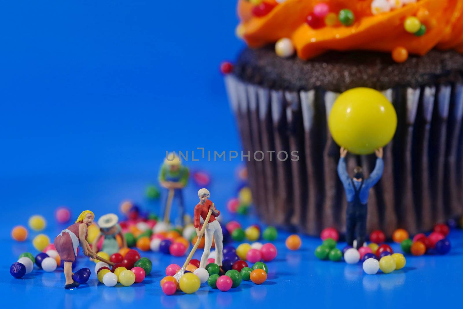 Miniature Plastic People Cleaning Up a Messy Cupcake