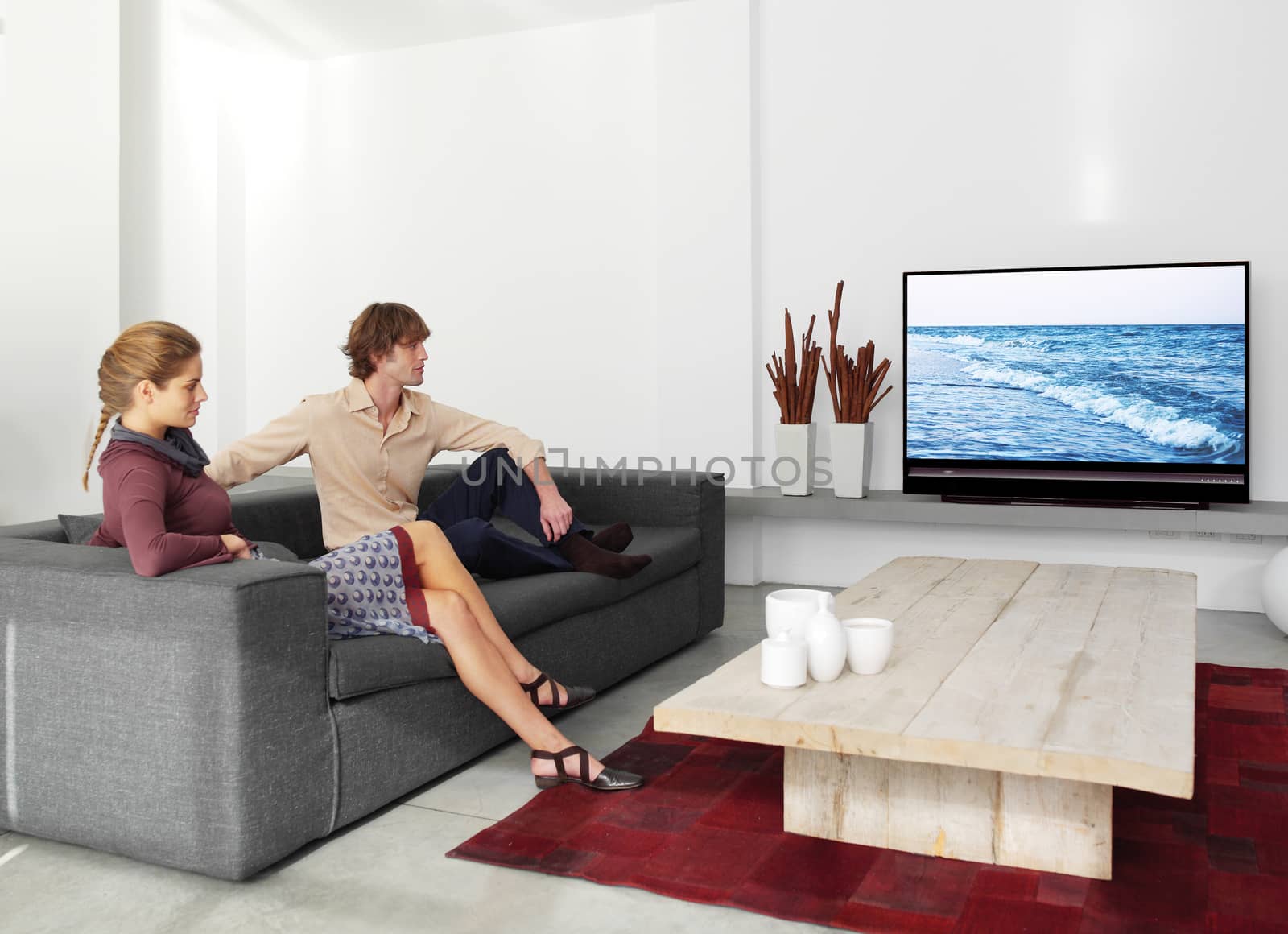 young couple sitting on the sofa watching tv in the living room 
