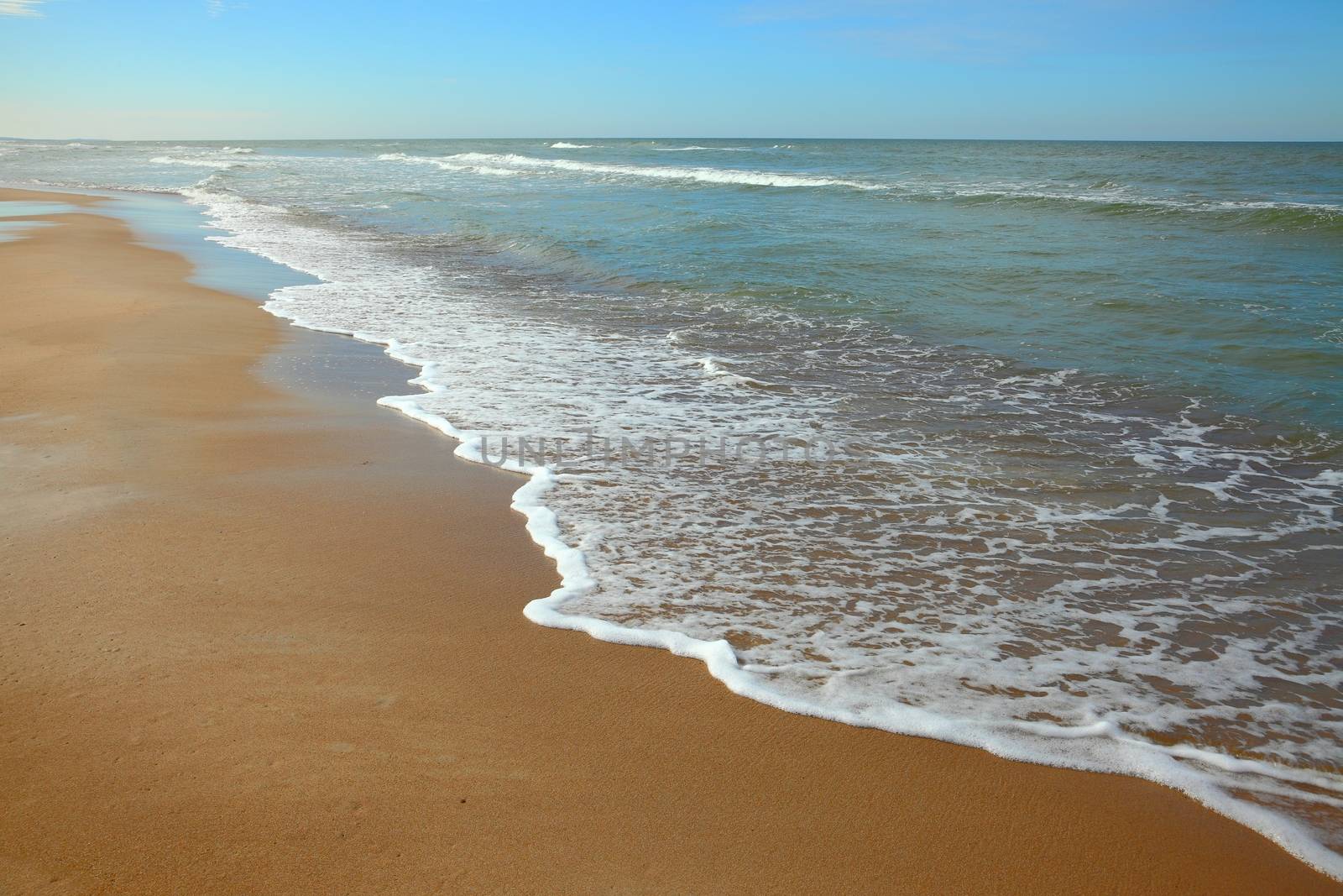 Sandy beach with waves of the see