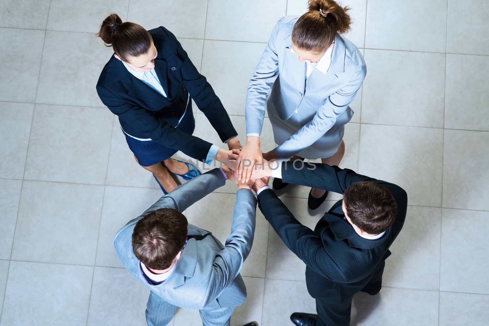 team of four businessmen with folded hands, a symbol of teamwork