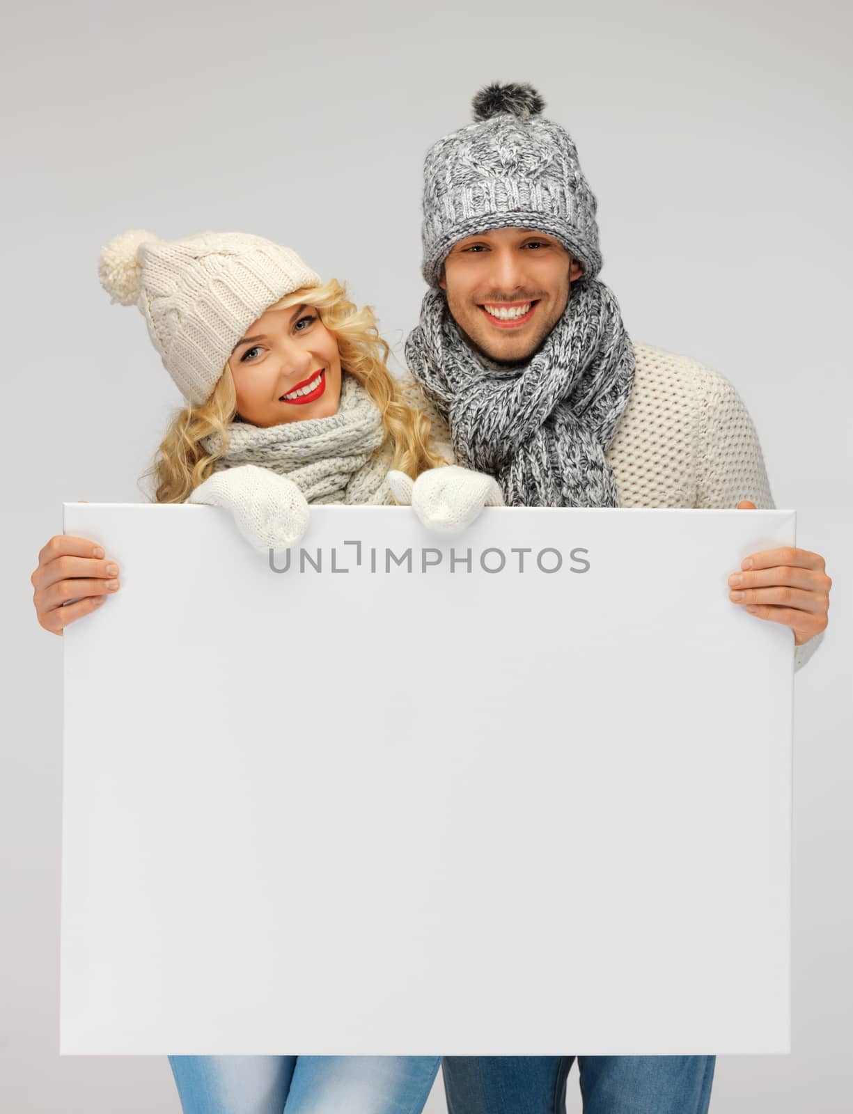 couple in a winter clothes holding blank board by dolgachov