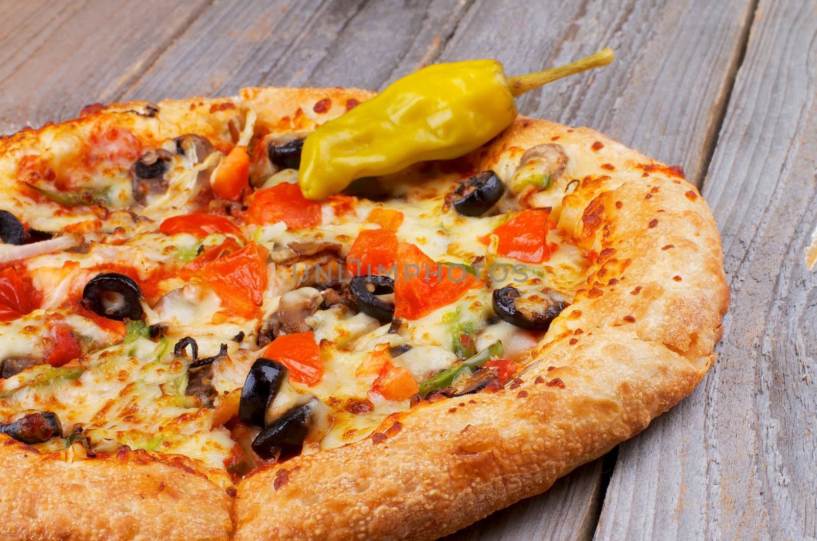 Part of Hot Vegetarian Pizza and Jalapeno Pepper closeup on Rustic Wooden background