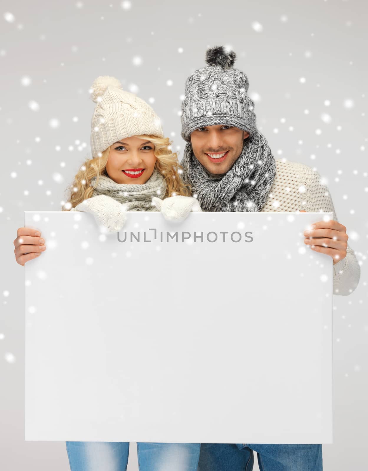 couple in a winter clothes holding blank board by dolgachov